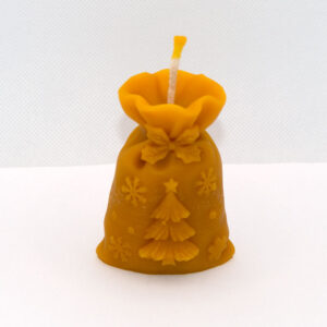 Mikulás csomag méhviasz gyertya felülről fotózva, sárga viasz színű, összekötött zsák alakú, fenyő és hópehely dekorációval.