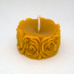 Méhviasz gyertya aminek az oldala rózsákkal van díszítve.