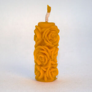 Méhviasz gyertya oszlop, melyet rózsa virágok díszítenek.