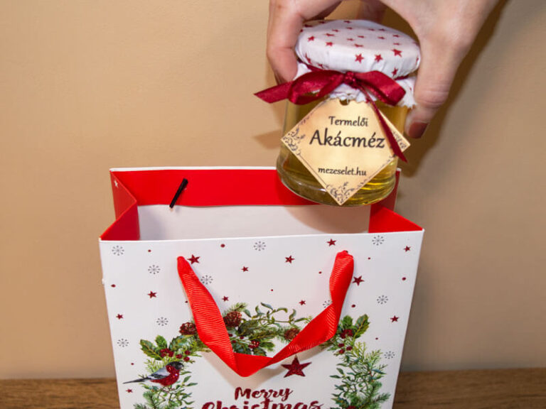Kéz, amely termelői mézet helyez egy karácsonyi ajándéktasakba – természetes termék ajándékcsomaghoz.